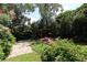 Private backyard featuring a cozy pergola with seating, surrounded by lush greenery and plants at 13637 13Th St, Dade City, FL 33525