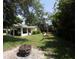 Expansive backyard with lush greenery, mature trees, a fire pit, and a carport with a vehicle at 13637 13Th St, Dade City, FL 33525