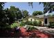 Charming backyard featuring a lush lawn, mature trees, a deck with seating, and a yellow house at 13637 13Th St, Dade City, FL 33525
