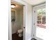 Half bath featuring a modern toilet, window with blue curtain, and access to the outdoor patio at 13637 13Th St, Dade City, FL 33525