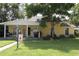 Charming yellow home with a welcoming front porch, mature trees, and a lush green lawn at 13637 13Th St, Dade City, FL 33525