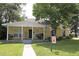 Inviting yellow home featuring a covered front porch, well-manicured lawn, and mature trees at 13637 13Th St, Dade City, FL 33525