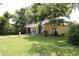 Charming yellow home with a covered front porch, lush lawn, and mature trees providing ample shade at 13637 13Th St, Dade City, FL 33525