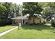 Welcoming yellow home with lush green lawn, mature shade trees, and a charming covered front porch at 13637 13Th St, Dade City, FL 33525