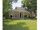 Quaint yellow home with a covered porch, swing, well maintained lawn, and mature shade trees at 13637 13Th St, Dade City, FL 33525