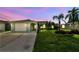 A charming single-story home with a well-maintained lawn, palm trees, and a wide driveway during sunset at 13909 Berkowitz Ave, Hudson, FL 34667