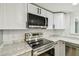 Modern kitchen showcasing stainless steel appliances, white cabinets, and marble countertops at 13909 Berkowitz Ave, Hudson, FL 34667