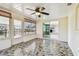 This sunroom features tile flooring, a ceiling fan, and windows that offer views of the waterfront at 13909 Berkowitz Ave, Hudson, FL 34667
