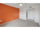 A light carpeted bedroom featuring a striking orange accent wall and white trim at 14800 Walsingham Rd # 1215, Largo, FL 33774