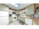 Bright kitchen with green cabinets, white appliances, and tile floors, illuminated by a skylight for a warm, inviting atmosphere at 1753 Ranchette Rd, Wesley Chapel, FL 33543