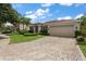 Beautiful home showcasing a manicured lawn, vibrant landscaping, and a spacious paver driveway leading to the garage at 19409 Wingrove Ln, Lutz, FL 33558