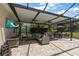 Spacious covered patio with comfortable seating, outdoor dining, a TV, and scenic backyard views at 19409 Wingrove Ln, Lutz, FL 33558