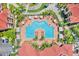 Aerial view of a community pool featuring lounge chairs, umbrellas, landscaping, and nearby community buildings at 2739 Via Capri # 1039, Clearwater, FL 33764