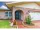 Close-up of the brick-arched front door with a well-kept garden bed and manicured lawn at 314 Circle Dr, Palm Harbor, FL 34683