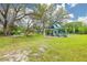 Community playground with a jungle gym, slides, swings, and picnic tables under mature trees on a grassy lawn at 314 Circle Dr, Palm Harbor, FL 34683