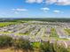 Aerial view of a residential community with a central lake surrounded by houses and greenery at 33657 Field Maple Loop, Wesley Chapel, FL 33545