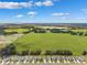 Scenic aerial view of houses bordering a vast green field, showcasing a peaceful community setting at 33657 Field Maple Loop, Wesley Chapel, FL 33545