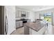 Bright kitchen features a large island with granite countertops, stainless steel appliances, gray cabinets, and tile floors at 33657 Field Maple Loop, Wesley Chapel, FL 33545