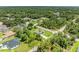 High angle shot of home with driveway and lawn bordered by mature trees in quiet neighborhood at 3682 Johnstown St, North Port, FL 34288