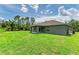 Exterior view of the house with a spacious lawn, and a covered back porch perfect for outdoor relaxation and entertainment at 3682 Johnstown St, North Port, FL 34288