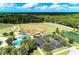 Aerial view of a baseball field with a playground, parking lot, and a pond surrounded by lush greenery and a clear blue sky at 3682 Johnstown St, North Port, FL 34288