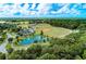 Aerial view of multiple baseball fields with a pond and a playground surrounded by lush greenery and a clear blue sky at 3682 Johnstown St, North Port, FL 34288