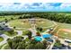 Aerial view of multiple baseball fields with a playground and parking lot surrounded by trees and a blue sky at 3682 Johnstown St, North Port, FL 34288