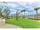 Outdoor play area with jungle gym, astroturf, mature trees, and red Adirondack chairs at 3682 Johnstown St, North Port, FL 34288