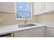 Bright kitchen featuring white cabinets, marble countertops, stainless steel sink, and natural light from window at 3940 Miramar S Way, St Petersburg, FL 33705