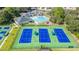Aerial view of tennis courts and swimming pool with clubhouse surrounded by manicured landscaping at 4495 Secretariat Run, Spring Hill, FL 34609
