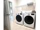 Well-lit laundry room features a side-by-side washer and dryer, with tan tile floors and a wire shelf above at 4950 Sandy Brook Cir, Wimauma, FL 33598