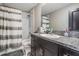 This bathroom features a shower-tub combo with dark wood cabinets and a gray and white patterned shower curtain at 5522 Appleton Shore Dr, Apollo Beach, FL 33572