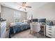 This carpeted bedroom has a work area set up with two monitors, a large window and a ceiling fan at 5522 Appleton Shore Dr, Apollo Beach, FL 33572