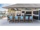 This outdoor kitchen has a stainless steel grill, a refrigerator, and a bar with blue chairs providing a stylish space at 5522 Appleton Shore Dr, Apollo Beach, FL 33572