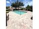 Community pool with paver deck, lounge chairs, lush landscaping, and seating under a covered area at 5644 Samter Ct, Tampa, FL 33611
