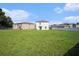 Expansive backyard featuring a large green lawn, white fence, and view of the rear of the two-story home at 6347 Ten Acre Ct, Zephyrhills, FL 33541