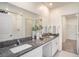 Modern bathroom with double granite countertop vanity and white cabinets with tiled shower and doorway to closet at 6347 Ten Acre Ct, Zephyrhills, FL 33541