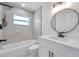 Modern bathroom showcasing a sleek vanity, round mirror, and a tiled shower/tub combination at 6352 Canton S St, St Petersburg, FL 33712