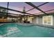 Covered pool with clear water, stone decking, and comfortable patio furniture, perfect for relaxation at 6715 Ranchwood Loop, New Port Richey, FL 34653