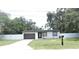 A clean single-Gathering home with a grassy yard, dark garage door, and white exterior at 814 W 131St Ave, Tampa, FL 33612