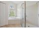 Bright bathroom with soaking tub, glass shower, and a unique window allowing for natural light at 9126 Cypress Keep Ln, Odessa, FL 33556