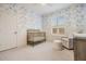 Charming Bedroom featuring a gold crib, chair and ottoman, beautiful floral wallpaper, and bright natural light from the window at 9126 Cypress Keep Ln, Odessa, FL 33556