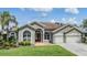 Charming single-story home with a well-manicured lawn, lush landscaping, and a two-car garage at 9126 Cypress Keep Ln, Odessa, FL 33556