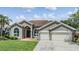 Charming single-story home with a well-manicured lawn, lush landscaping, and a two-car garage at 9126 Cypress Keep Ln, Odessa, FL 33556