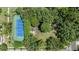 Aerial view of a blue tennis court surrounded by lush greenery with an adjacent gazebo at 9126 Cypress Keep Ln, Odessa, FL 33556