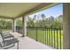 Relax on this covered balcony with a serene view of lush greenery and open space at 10701 Morning Dew Way, Tampa, FL 33647