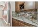 Elegant bar area featuring granite countertops, wine glass storage, and stylish backsplash at 10701 Morning Dew Way, Tampa, FL 33647