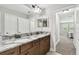 Bathroom featuring dual sinks, granite countertops, and dark cabinetry with a view of the bedroom at 10701 Morning Dew Way, Tampa, FL 33647