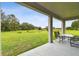 Covered patio with outdoor seating overlooking a large green lawn and pond at 10701 Morning Dew Way, Tampa, FL 33647