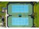 Aerial view of tennis courts with blue playing surface and green perimeter at 10701 Morning Dew Way, Tampa, FL 33647